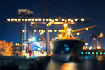Blur bokeh of harbor with large ship and crane at night.