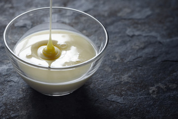 Pouring condensed milk in the glass bowl horizontal