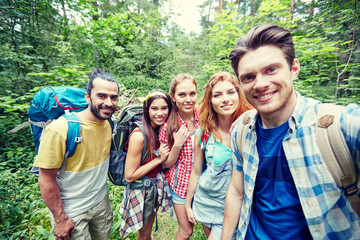 friends with backpack taking selfie in wood