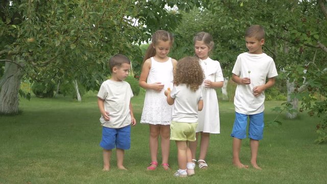 Little girl gives the kids lollipops in the garden