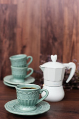 Cup of coffee and Italian coffee maker in blue, scent of lavender. Dark wooden background