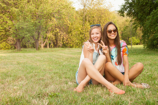 Outdoor lifestyle portrait of two best friends hipster girls wearing stylish bright outfits, t-shirts, denim shorts and glasses, going crazy and having great time together