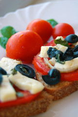 Bruschetta with tomatoes, black olives, goat cheese, herbs and oil on toasted bread