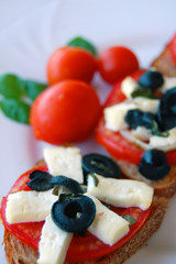 Bruschetta with tomatoes, black olives, goat cheese, herbs and oil on toasted bread