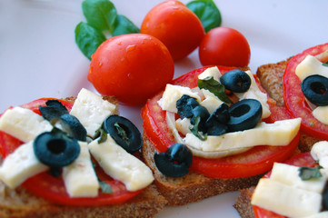 Bruschetta with tomatoes, black olives, goat cheese, herbs and oil on toasted bread