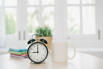 Vintage alarm clock with cup of coffee on wooden background,flare light