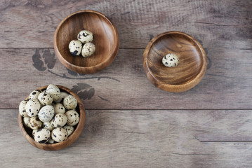 Obraz na płótnie Canvas Three wooden bowls with quail eggs. Rustic wood background, diffused natural light. A different type of concept image for Easter. Copy space.
