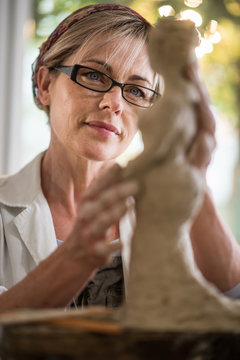 a nice 40 year  woman with glasses who shapes a statue