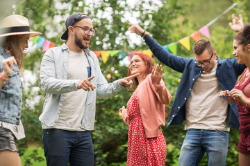 happy friends dancing at summer party in garden