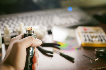 man prepares coil electronic cigarette smoking tasty vape juice. Device for the vaporization...