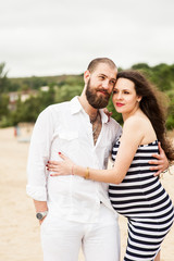 Obraz premium Beautiful young pregnant woman with man on the beach feel peace and tranquility