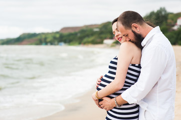 Beautiful young pregnant woman with man on the beach feel peace and tranquility