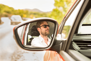 Man (driver) reflected in a car wing mirror