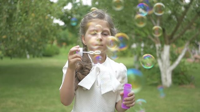 A sweet girl blows a bubbles in the garden