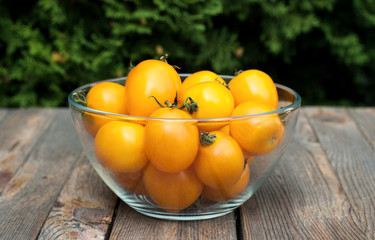 Bowl with yellow tomatoes on the wooden table