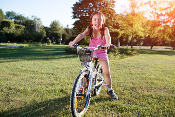 Fototapeta premium girl riding bicycle in summer sunset in the park