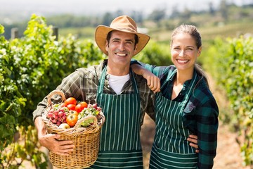 Portrait of happy farmer couple holding a basket of vegetables