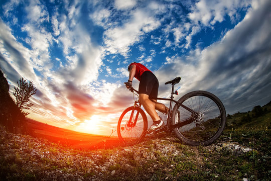 cyclist riding mountain bike on rocky trail at sunrise