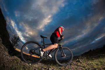 Fototapeta na wymiar cyclist standing with mountain bike on trail at sunset