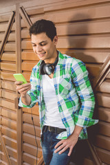 Cool millennial young man with smart phone and headphones