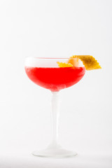Orange cocktail beverage with lime and berry in martini glass on white background