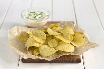 Potato chips with dipping sauce on a white table.