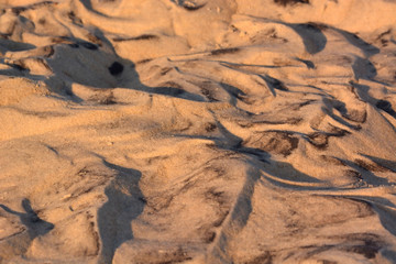 Black Swirls in the Sand after High Tide has Washed up onto the Beach in the Night