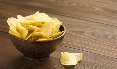 Potato chips in a bowl on wooden table. - 121580014