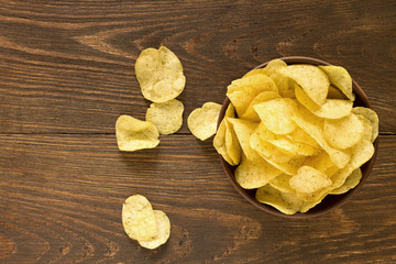 Potato chips in bowl on a wooden background, top view. - 121580019
