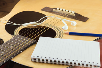 Fototapeta premium Notebook and pencil on guitar, Writing music..