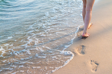 Lonely girl walking on the sand with footprints