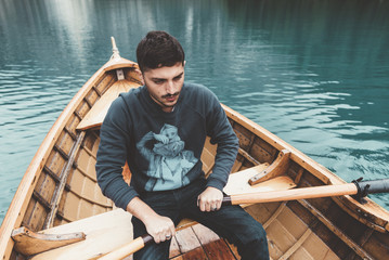 Man rowing a wood boat at Braies lake - 121582225