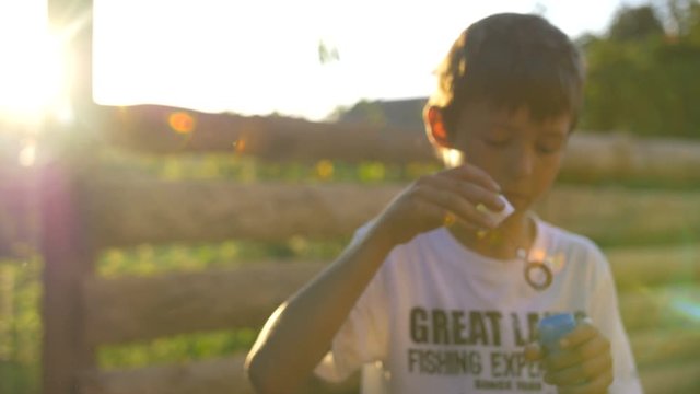 Boy Blowing Soap Bubbles At Sunset