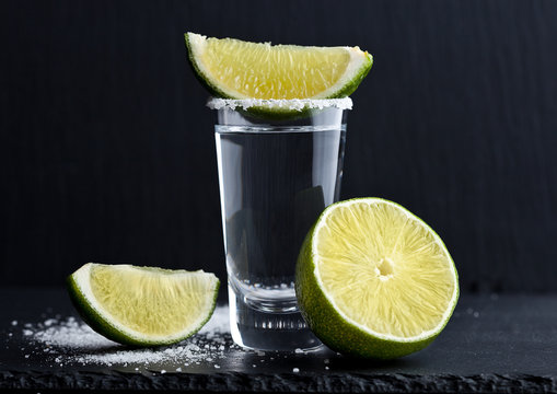 Tequila silver shot with lime slices and salt on stone board