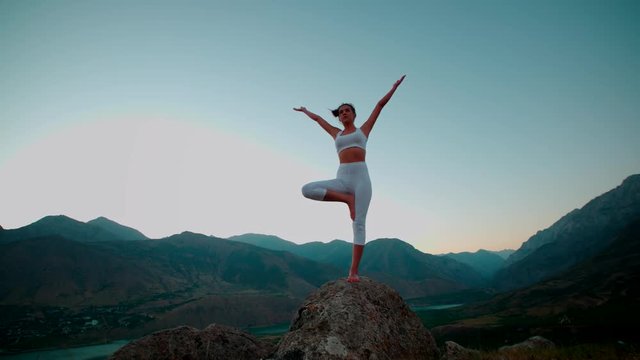 4K beautiful girl in white clothes doing yoga on the beautiful backdrop of the mountains,slow motion