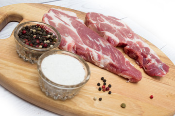 Two raw plump  pork neck chops with spices on wooden cutting board