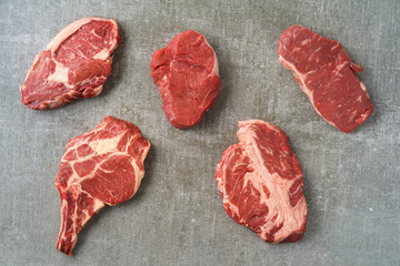 Variety of different beef steaks on grey stone