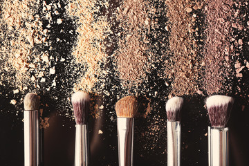 Make up brushes and colourful eye shadows on black background