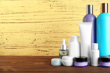 Different cosmetic bottles on yellow wall background