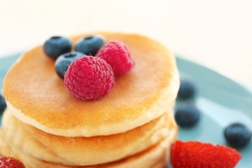 Delicious pancakes with berries on blue plate, closeup