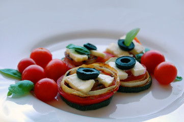 Grilled zucchini slices with tomatoes, black olives, goat cheese and basil