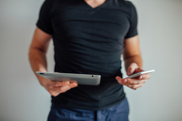 Man is using pc tablet and holding phone.