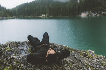 Man relaxing on a cliff on Braies lake - 121594883