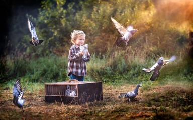 Little pigeon fancier. Boy playing with flying pigeons.
