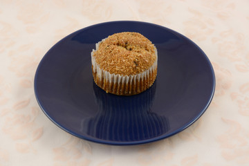 One raisin breakfast muffin with crushed cereal topping on plate