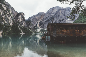 wooden jetty and building on Braies lake with mountains and trees - 121597205