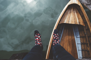 View of legs and feet with socks on Braies lake with wood boat
