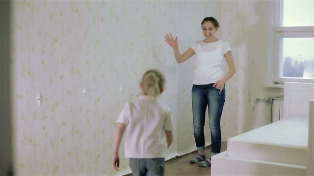 A girl giving a high five to her mother and they remove wallpaper. Slow motion.