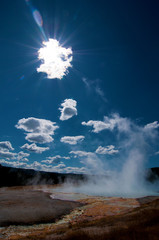 Rauchender Geysir im Yellowstone Park mit der Morgensonne hinter einer Wolke