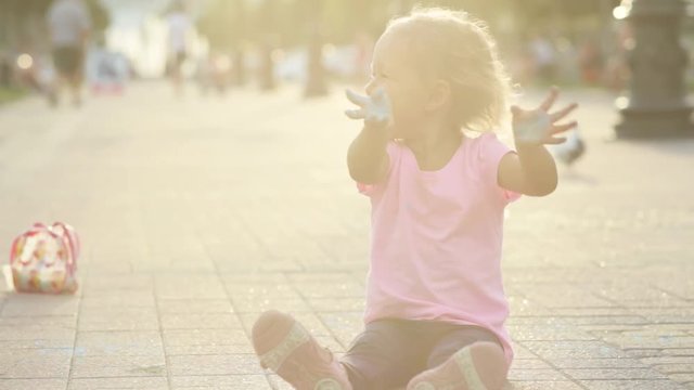 Cute girl soiled with chalk, having fun and show her dirty hands to the camera